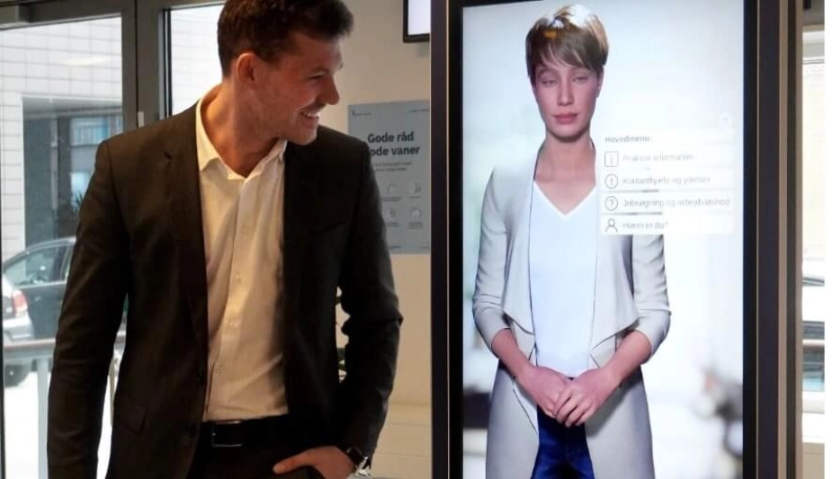 Anders Winnerskjold (S), rådmand for Sociale forhold og Beskæftigelse i Aarhus, hilser på receptionisten Trothilde, er bygget på kunstig intelligens.