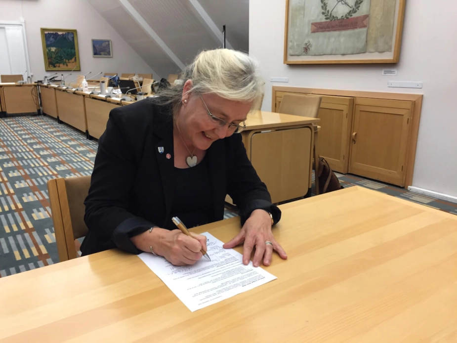 En glad borgmester underskriver budgetaftalen.